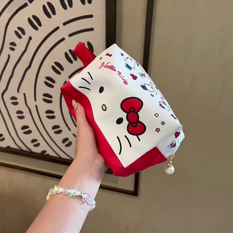 Hand holding a Hello Kitty pouch with a decorative wall in the background