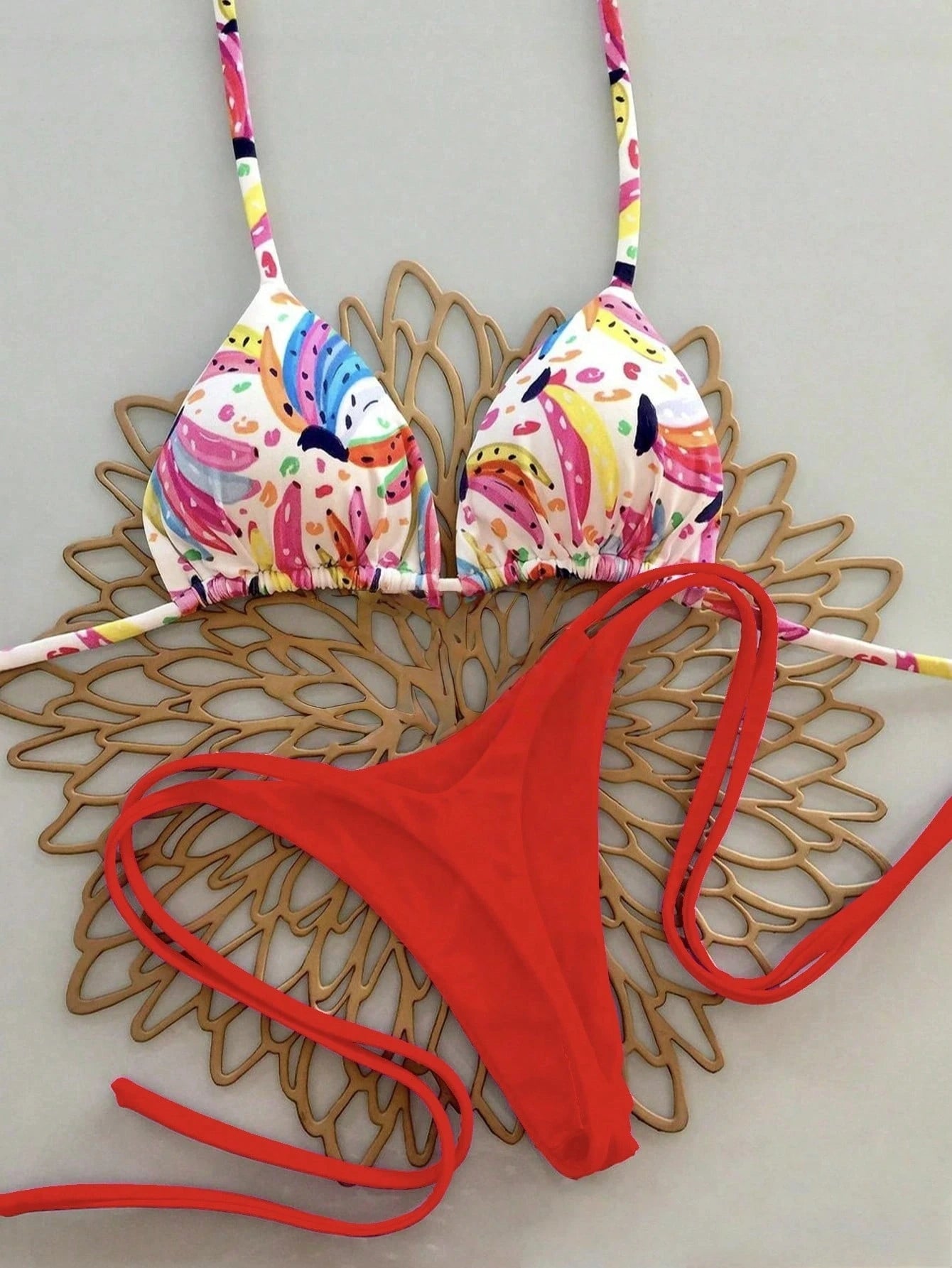 Colorful bikini top and red bottom on a decorative wooden surface