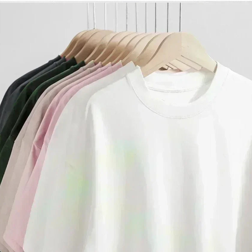 Set of plain white shirts on hangers against a light background
