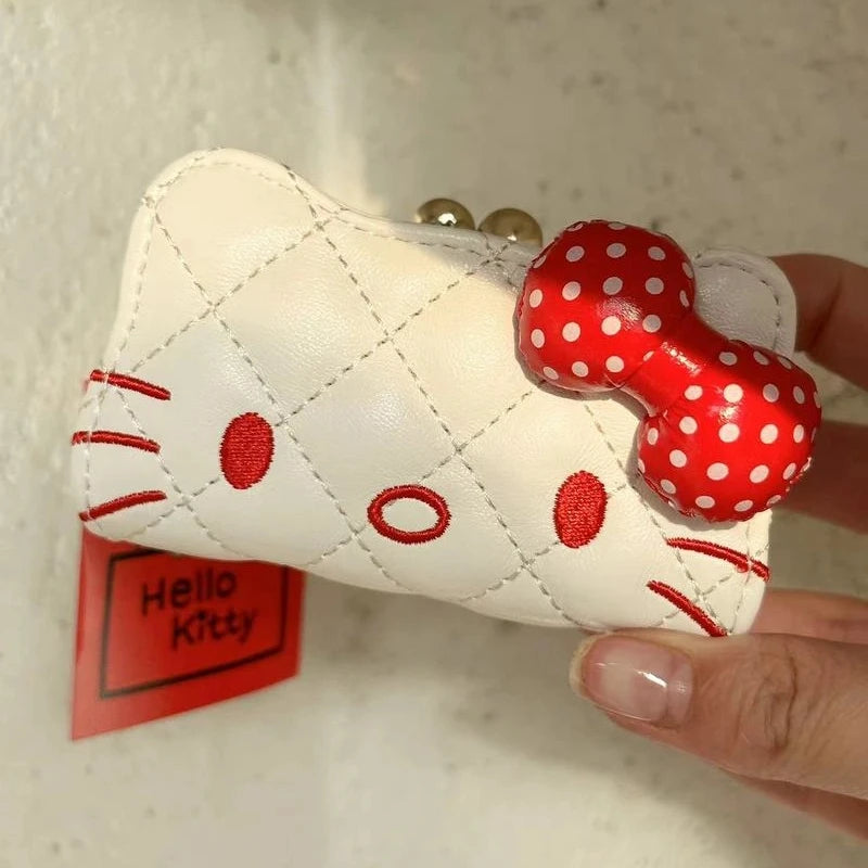 White quilted pouch with red polka dot bow held by a hand, with 'Hello Kitty' tag in the background.