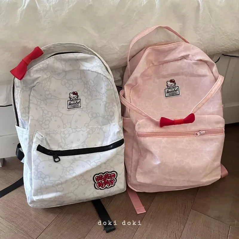 Two backpacks, one white and one pink, with visible branding on a wooden floor.
