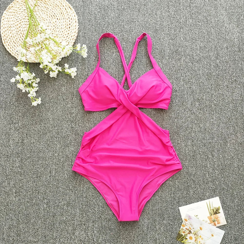 Pink bikini set on a textured gray surface with flowers and a hat.