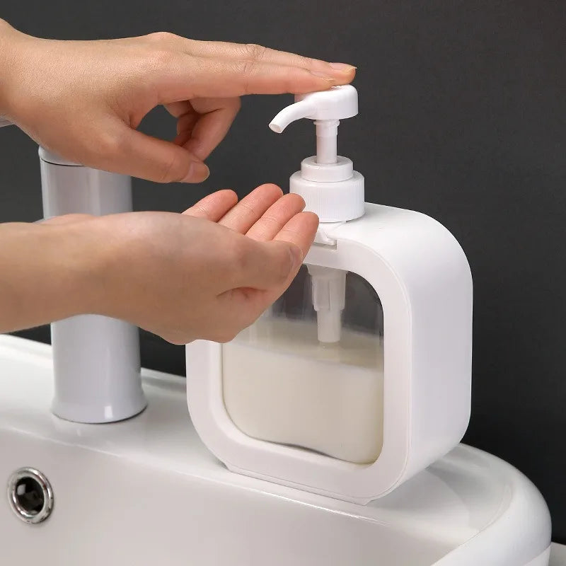 Hand using a white soap dispenser on a sink with a dark background