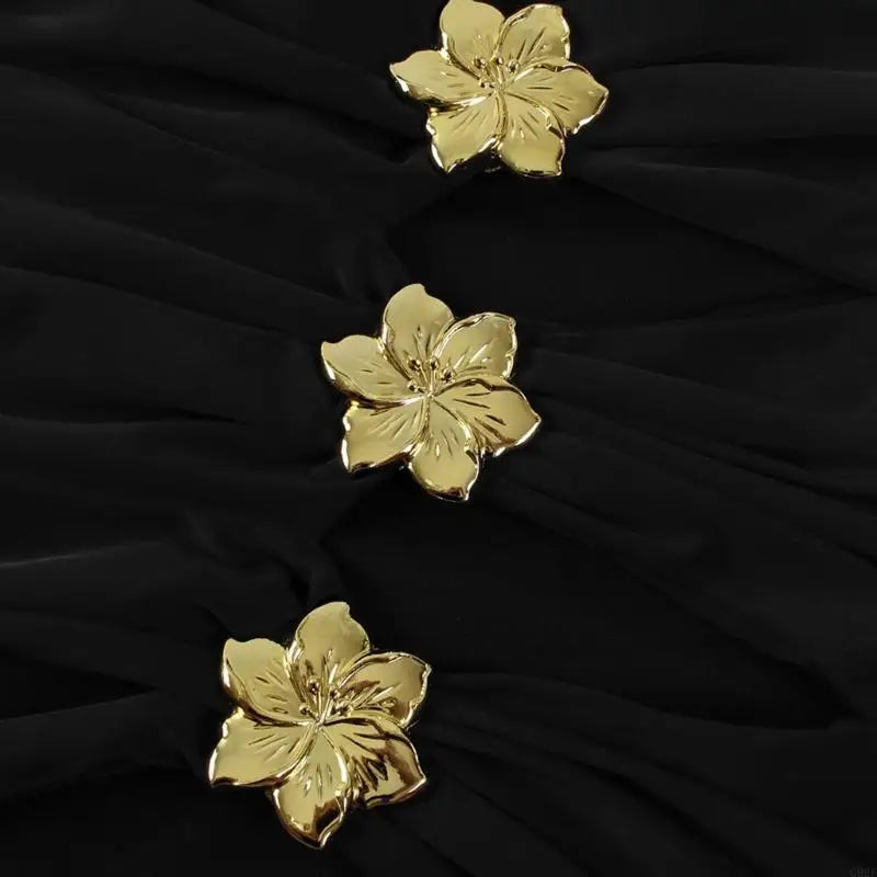Three gold floral buttons on a black fabric background