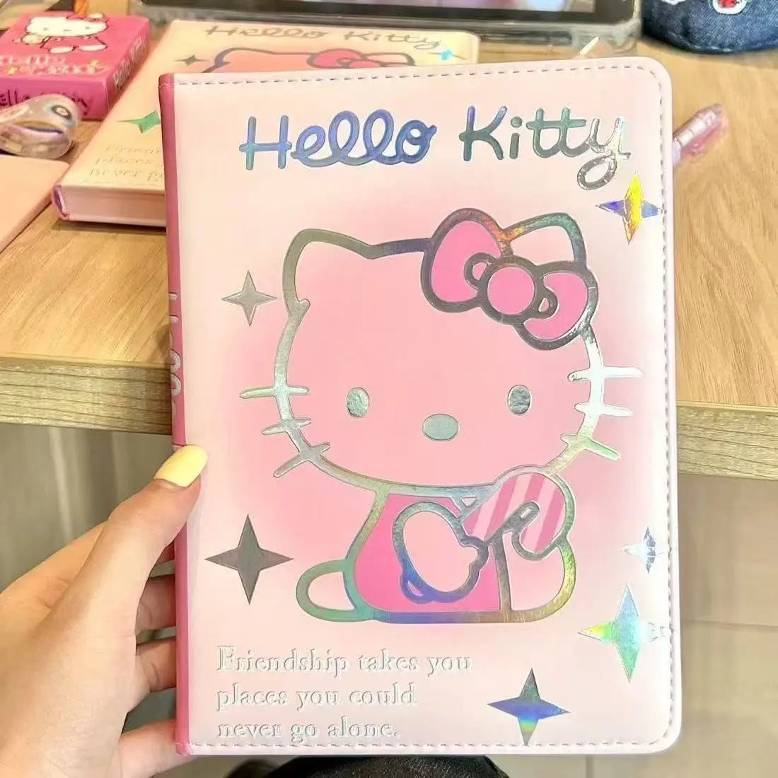 Hello Kitty notebook held by a hand on a wooden surface