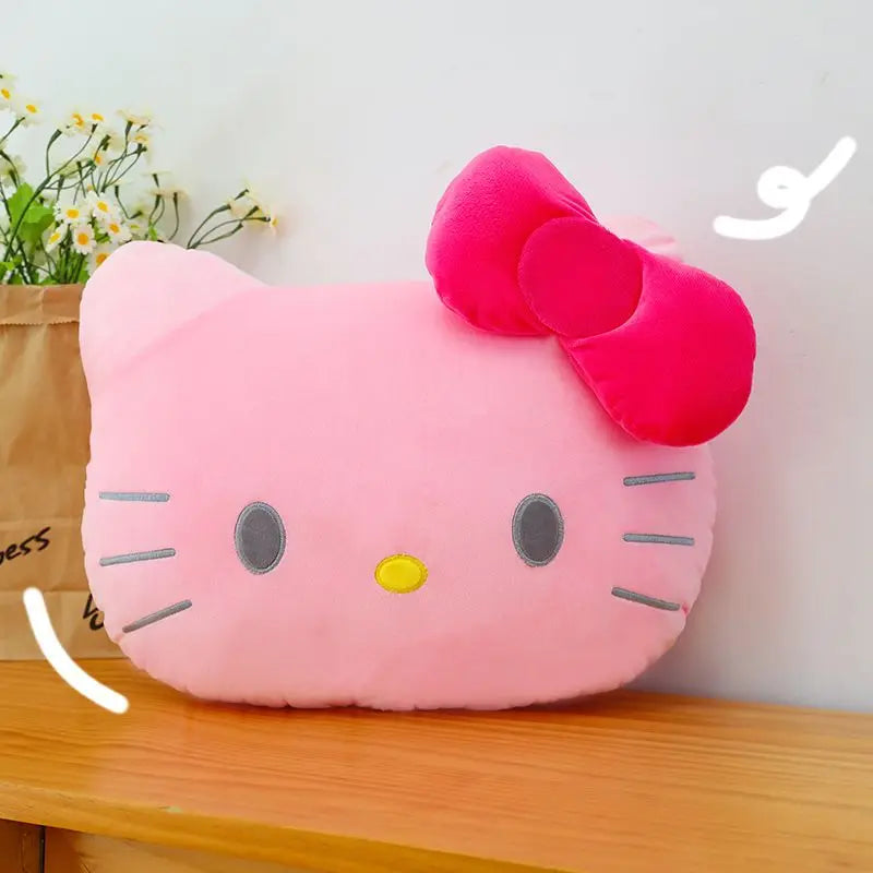 Pink Hello Kitty cushion with a red bow on a wooden surface.