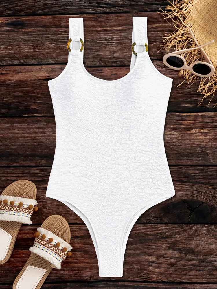 White swimsuit on a wooden surface with sandals and a hat.