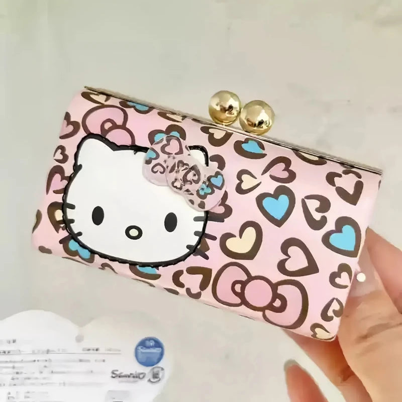 Pink wallet with Hello Kitty design held by a hand against a light background