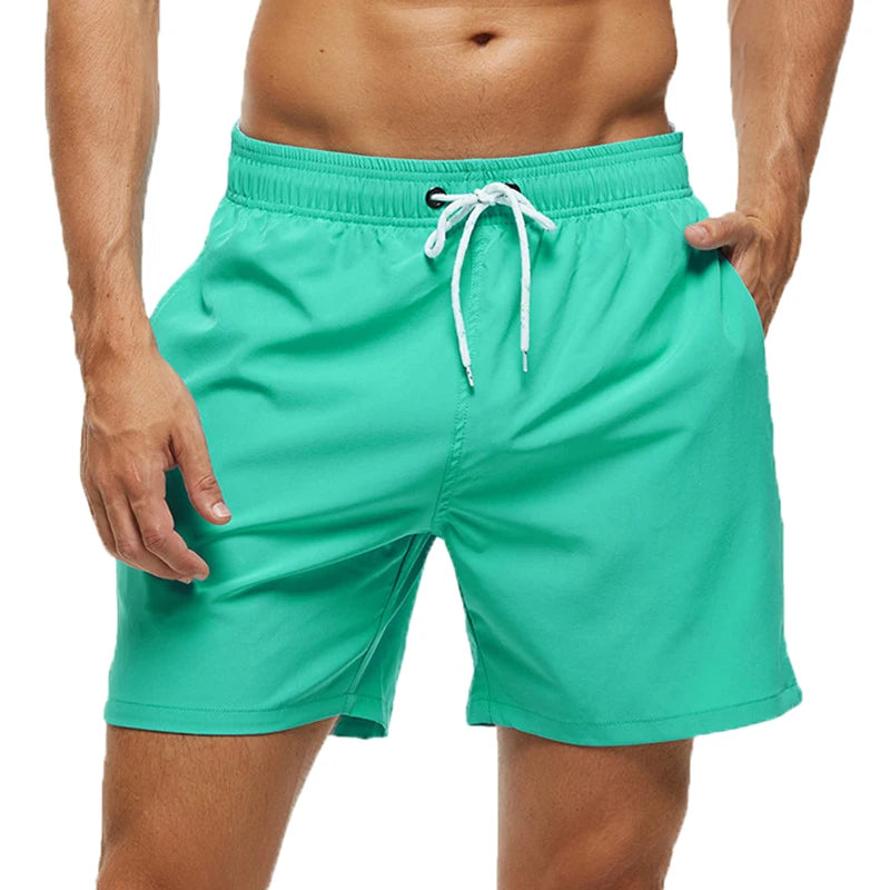 Turquoise swim shorts with a white drawstring on a white background