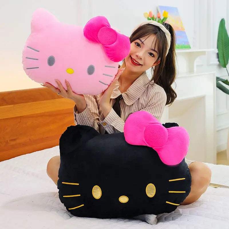 Woman holding a large black and pink Hello Kitty pillow on a bed.