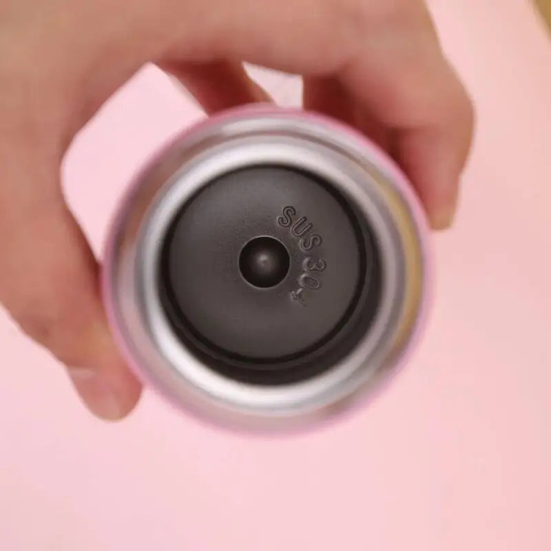 Close-up of a pink container with a black lid on a pink background