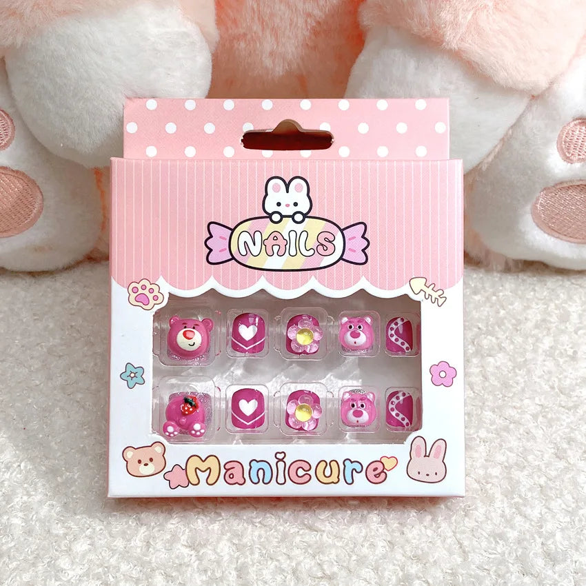 Box of false nails with cute designs on a soft surface