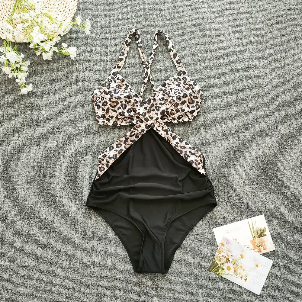 Leopard print bikini top and black high-waisted bottoms on a gray surface with flowers and cards.