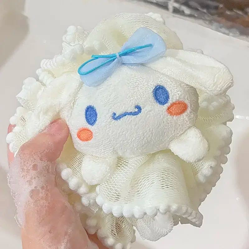 Kitty bath sponge plush toy with a face design held by a hand in a soapy water setting