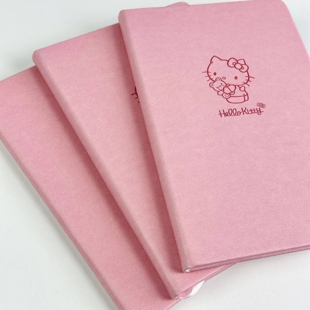 Three pink notebooks with Hello Kitty logo on a white background