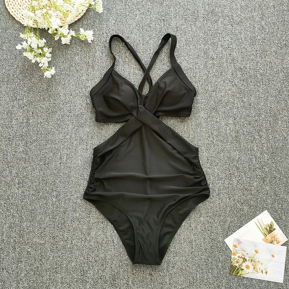 Black swimsuit on a textured gray surface with flowers and a card.