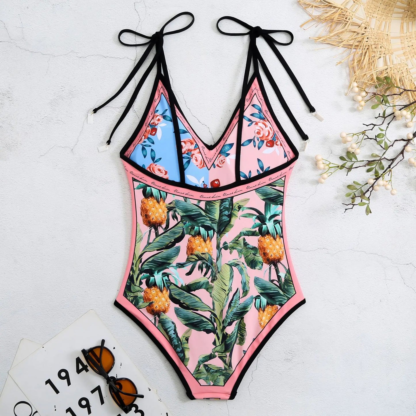Multicolored swimsuit with floral and pineapple patterns on a light background