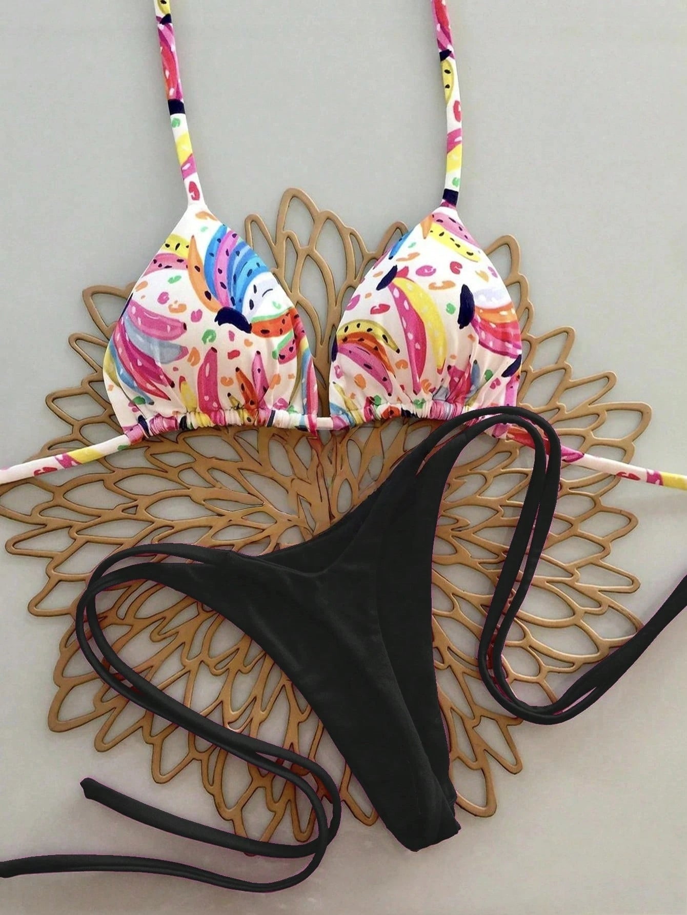 Colorful bikini top and black bottom on a decorative wooden surface