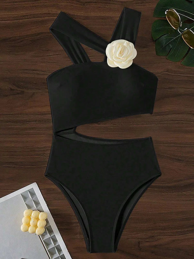 Black bikini set with a white flower detail on a wooden surface