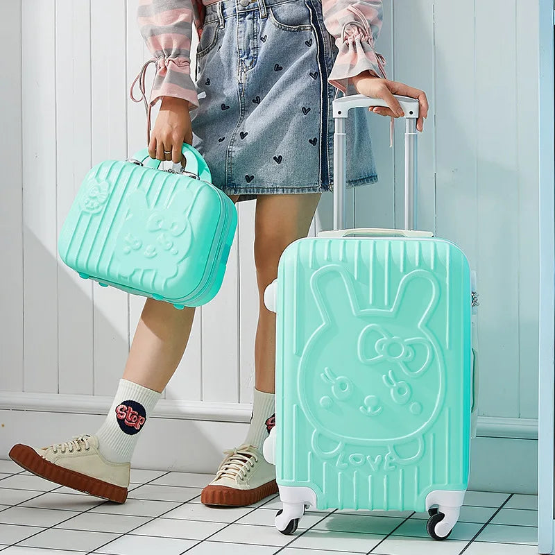 Person holding a mint green suitcase with a bunny design and a smaller matching handbag.