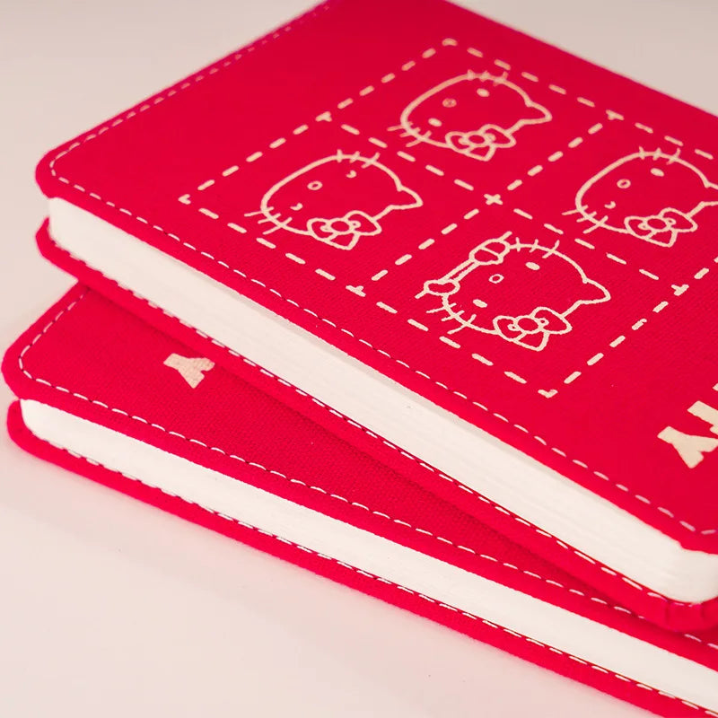Red 'Hello Kitty' notebook and cover on a pink background
