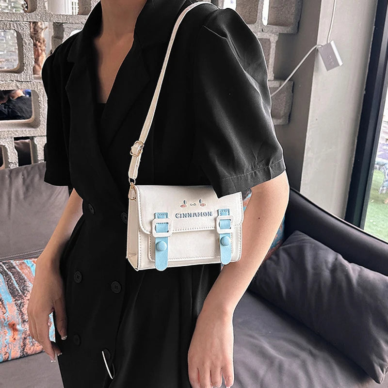 Person holding a white handbag with blue accents indoors