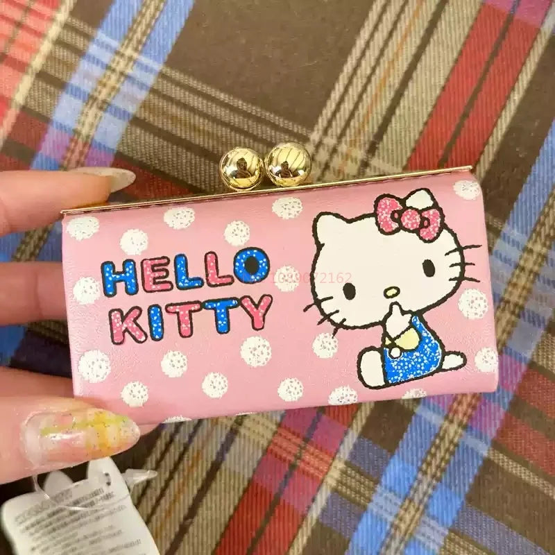 Pink Hello Kitty clutch bag with gold accents on a plaid background