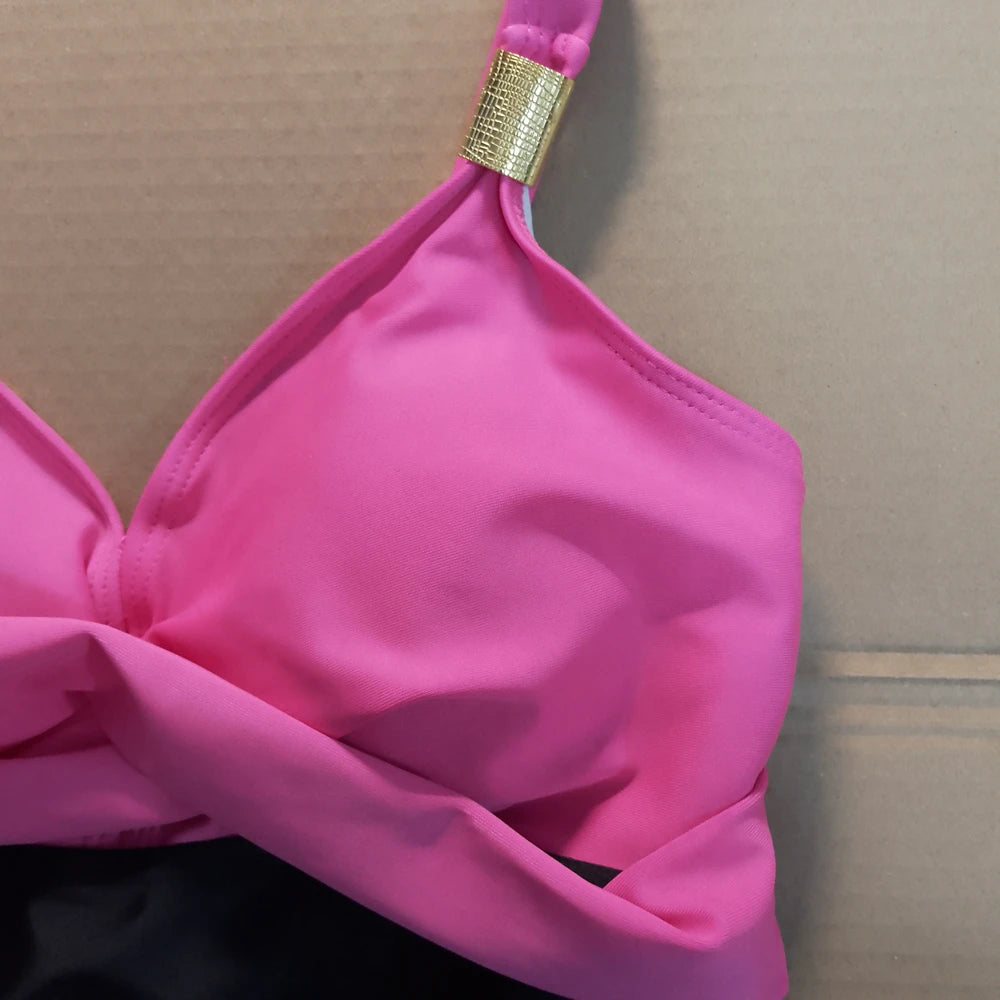 Pink bikini top with a gold clasp on a neutral background
