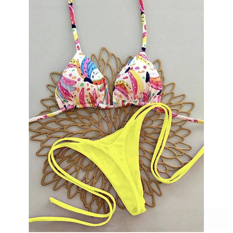 Colorful bikini set with floral top and yellow bottom on a decorative wooden surface.
