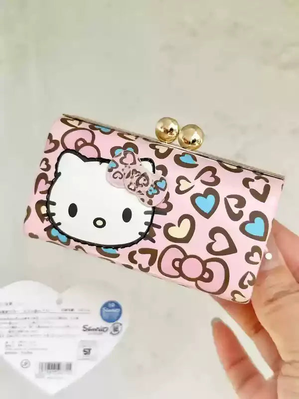 Hello Kitty clutch bag with heart pattern held by a hand on a light background