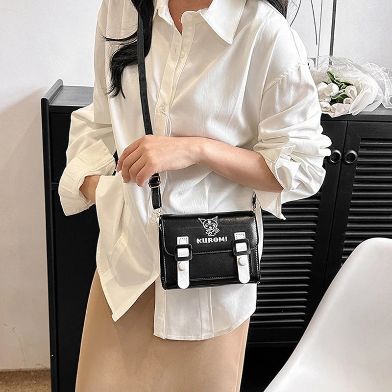 Person wearing a white shirt holding a black handbag with a visible brand logo.