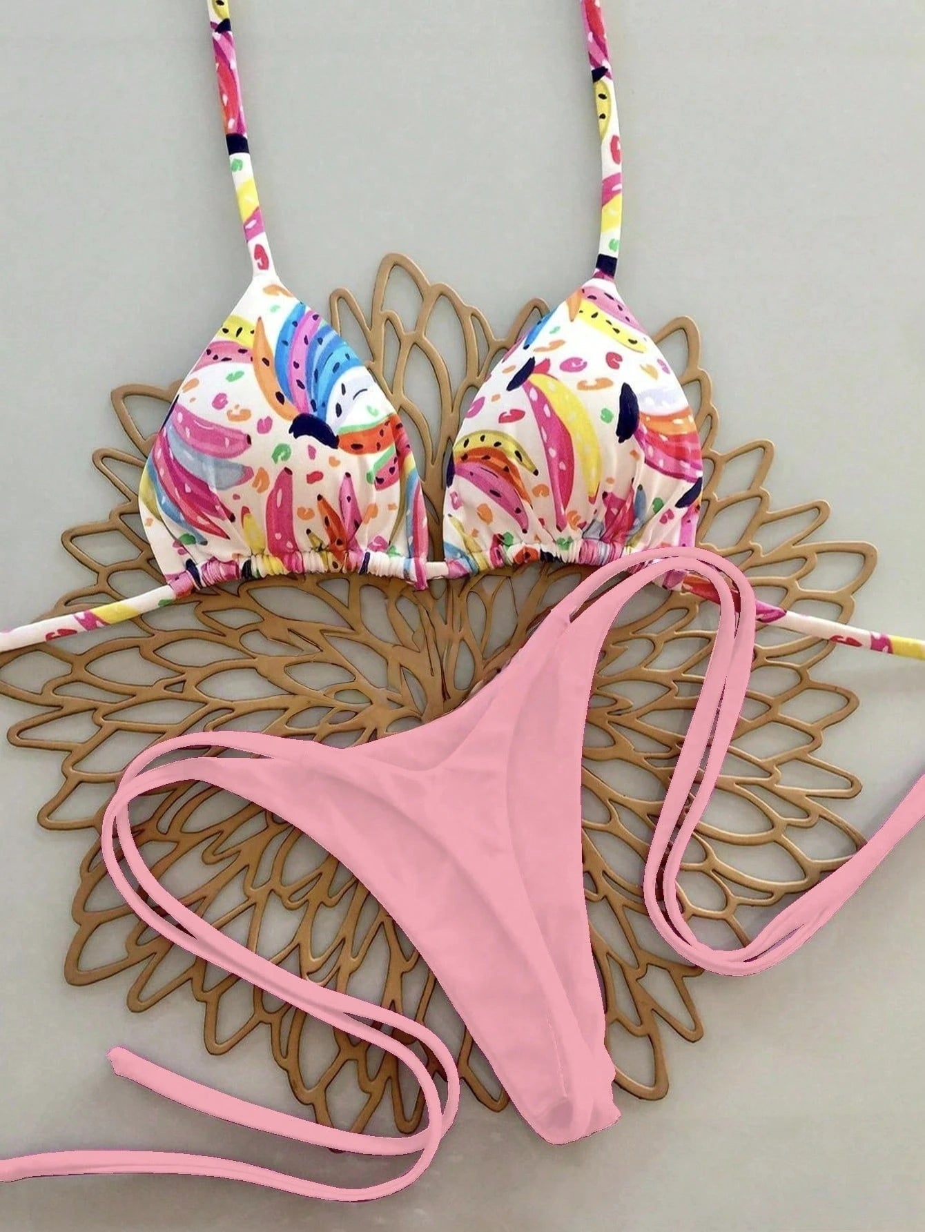 Colorful bikini top and pink bottom on a decorative wooden surface