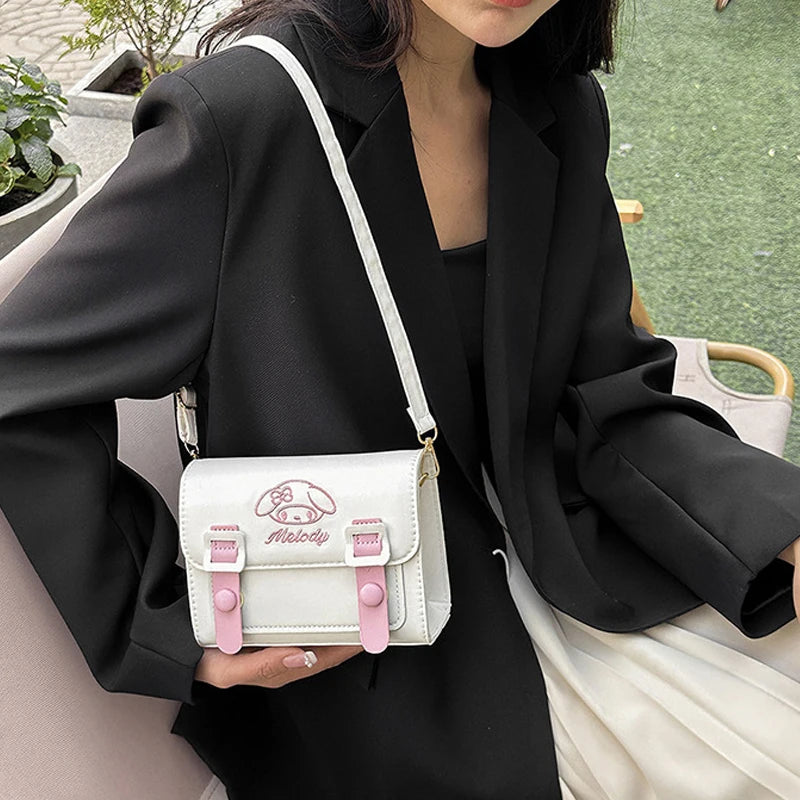 Person holding a white and pink bag with a logo, sitting outdoors.