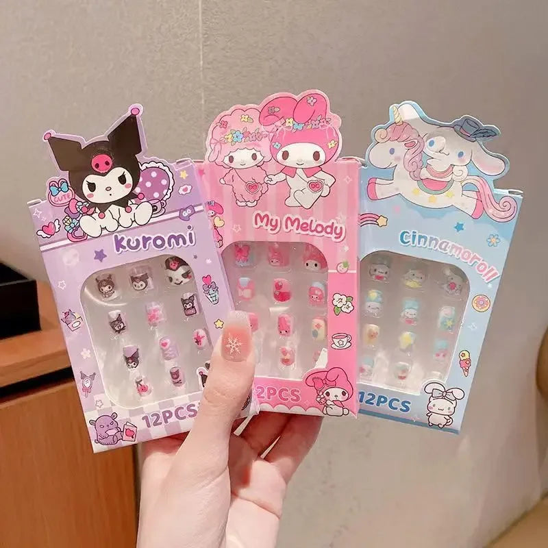Three cartoon character nail art packages held by a hand against a neutral background