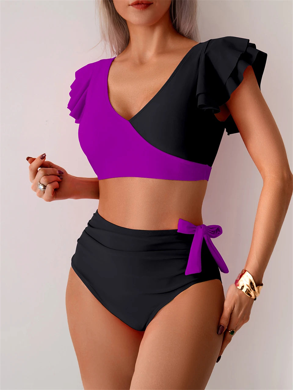 Purple and black two-piece swimsuit with ruffled top on a plain background