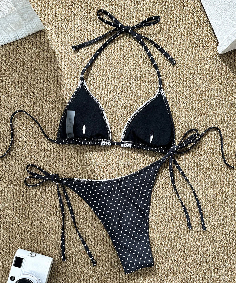 Black polka dot bikini set on a beige carpet with a camera in the corner.