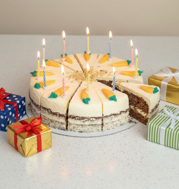Carrot cake with candles on a white surface with gift boxes around
