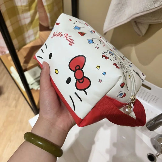 Hand holding a Hello Kitty pouch with a red bow design.