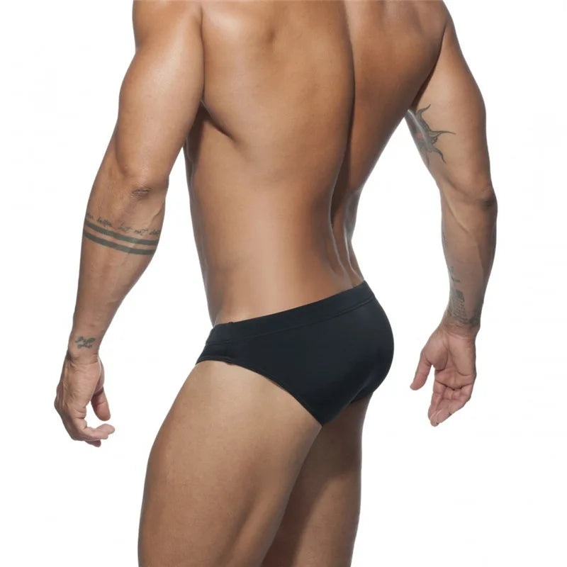Person wearing black swim briefs on a white background