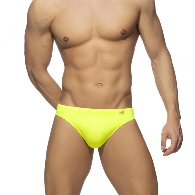 Man wearing bright yellow swim briefs on a white background