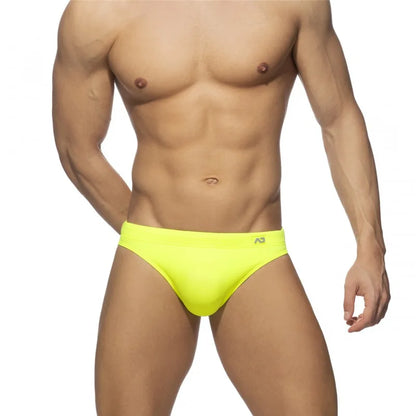 Man wearing bright yellow swim briefs on a white background