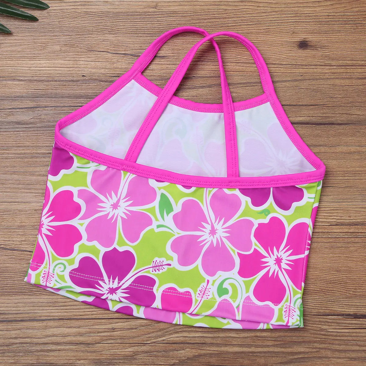 Floral-patterned bikini top with pink straps on a wooden surface