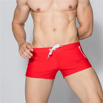Red swim shorts with a white drawstring on a gray background