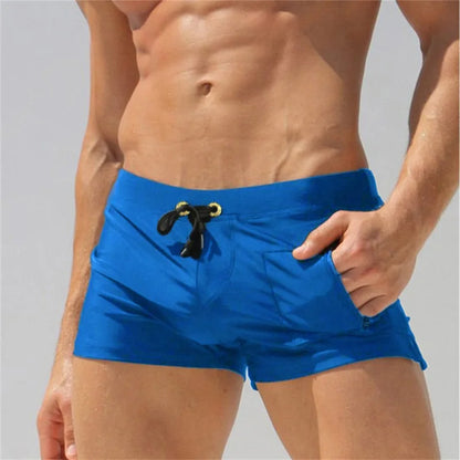 Blue swim shorts worn by a person on a plain background