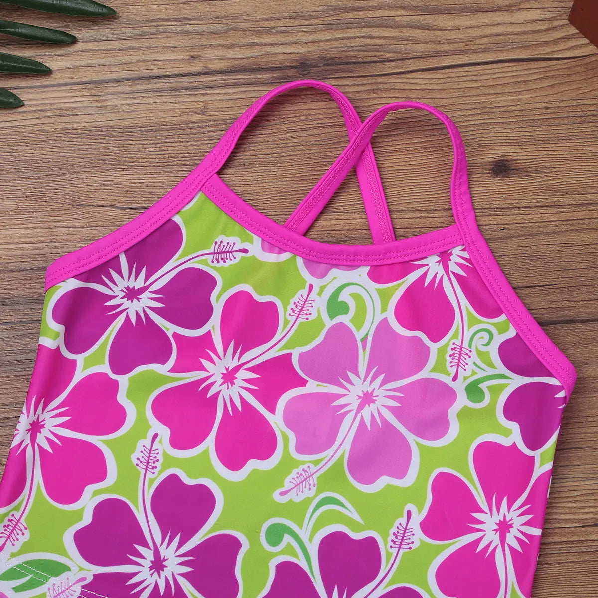 Pink and green floral bikini top on a wooden surface