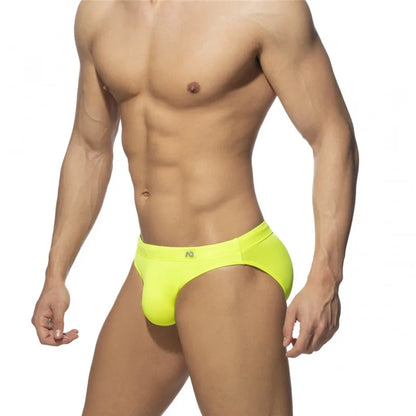 Man wearing bright yellow swim briefs on a white background