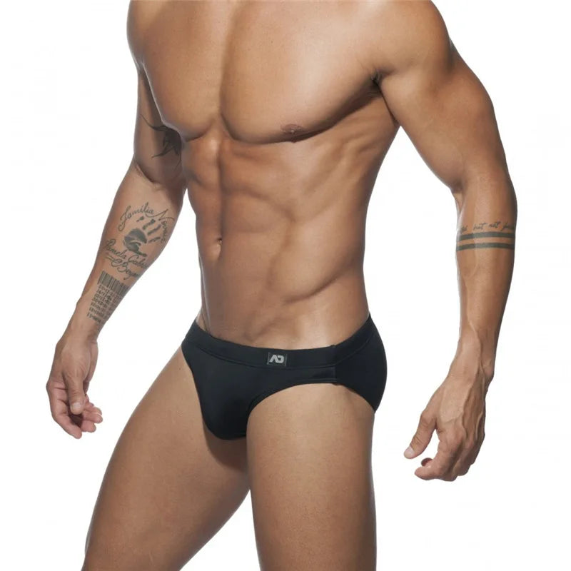 Man wearing black swim briefs on a white background
