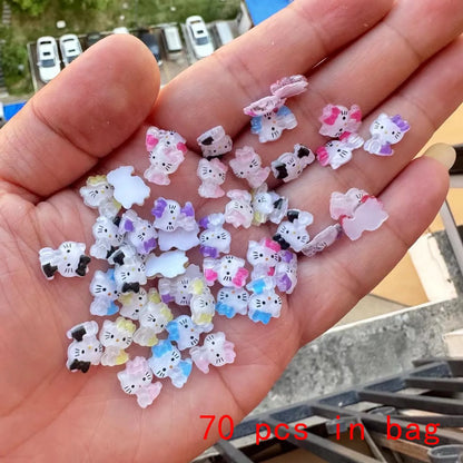 Hand holding small cat-shaped figurines with a visible text '70 pcs in bag' in an outdoor setting.