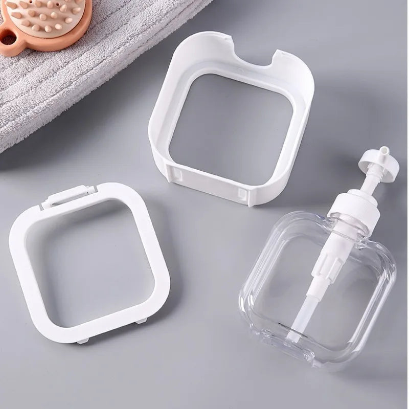 Clear plastic bottle with pump and white square containers on a gray surface