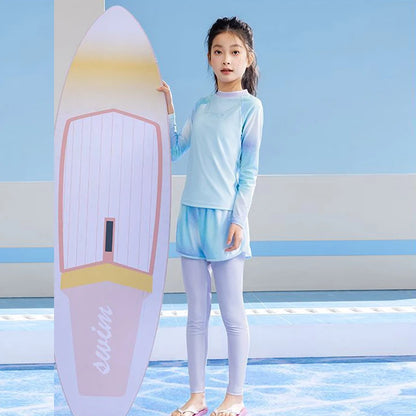 Young girl in a light blue swimsuit standing next to a surfboard with a blue background